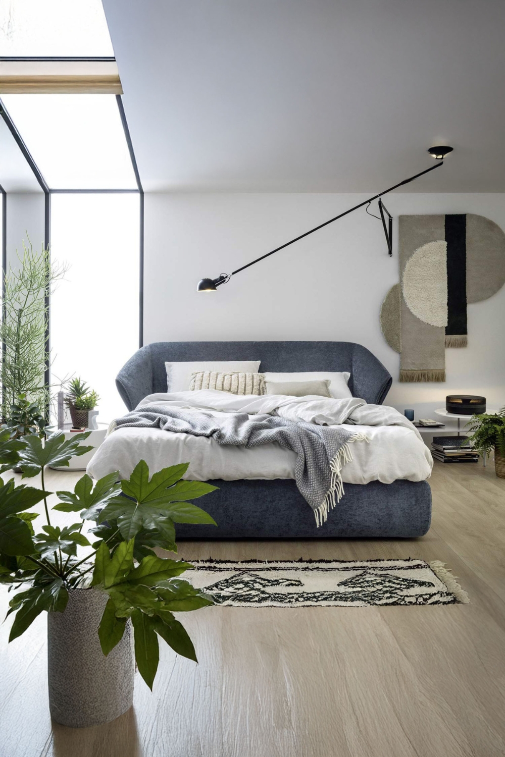 camera da letto arredata in modo confortevole con un grande letto imbottito e diverse piante