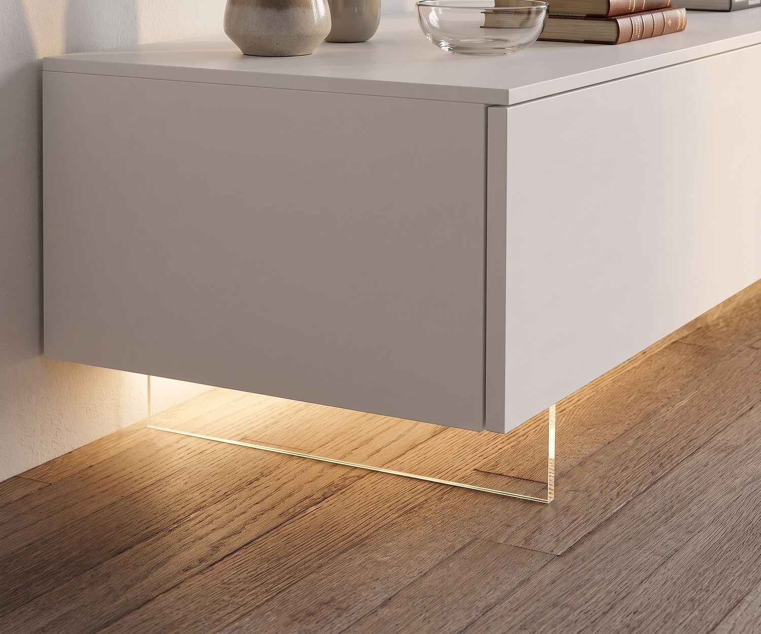 Zoccolo TV trasparente Livitalia per porta TV Zoccolo TV trasparente Livitalia per un effetto sospeso del mobile TV basso con luce LED su parquet.