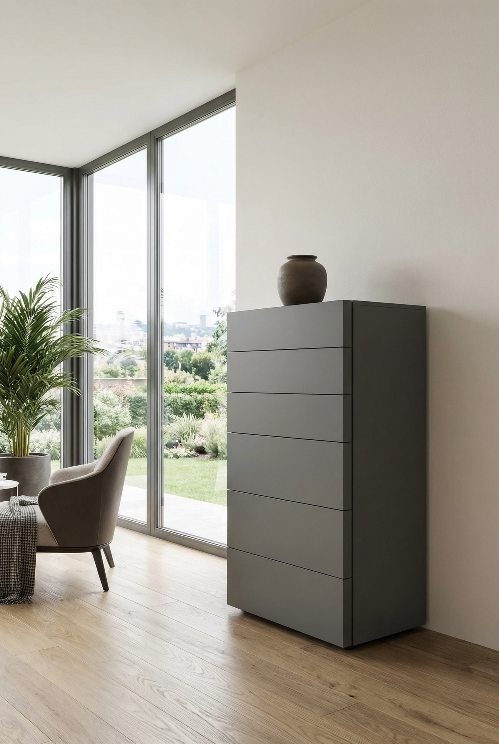 Una cassettiera alta moderna, senza maniglie, in elegante grigio scuro opaco, messa in scena davanti a una parete chiara come mobile minimalista e di forte contrasto. Una cassettiera alta moderna, senza maniglie, in elegante grigio scuro opaco, messa in scena davanti a una parete chiara come mobile minimalista e di forte contrasto.