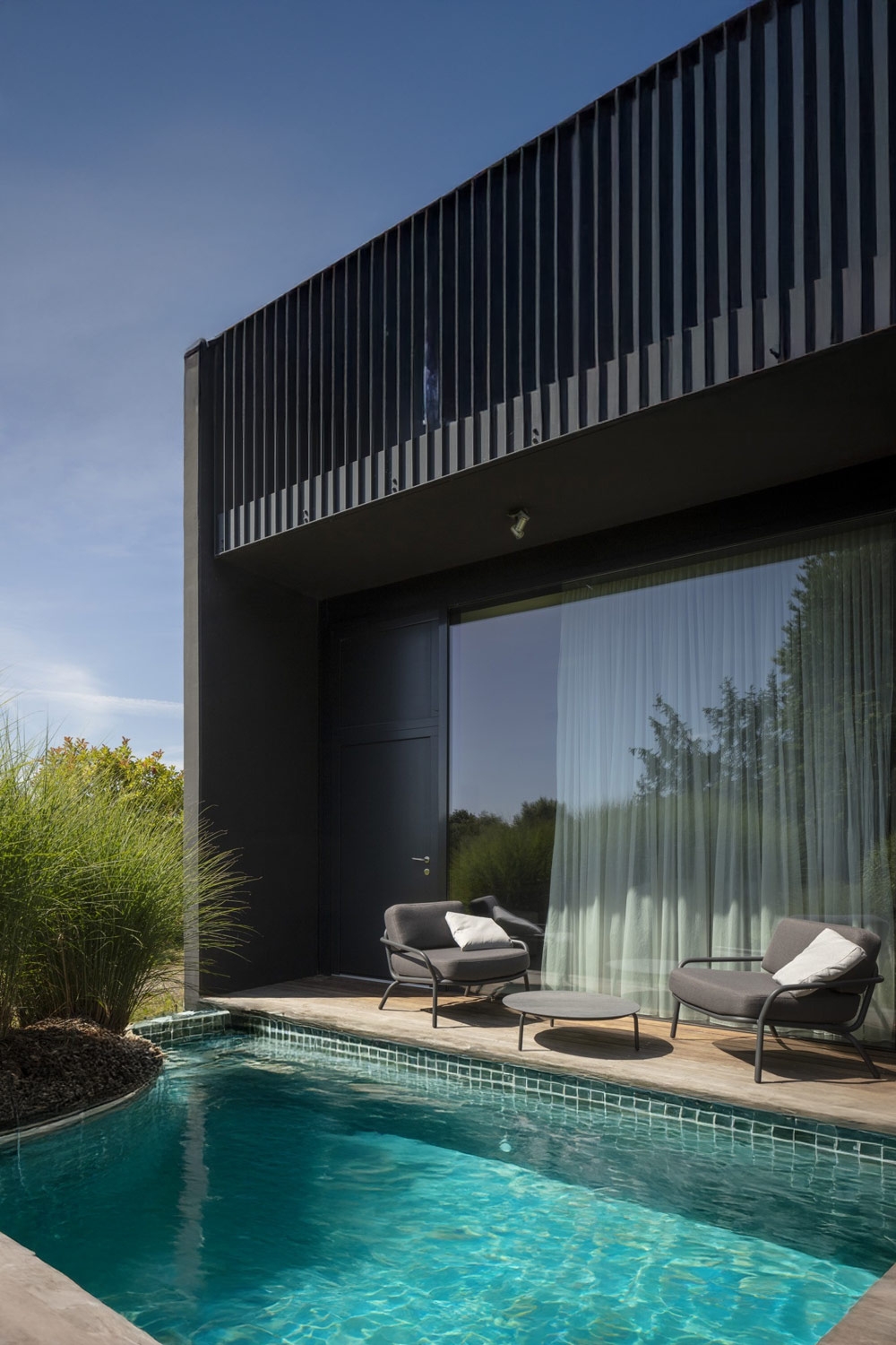 moderne ampie poltrone imbottite con tavolo dietro una piscina