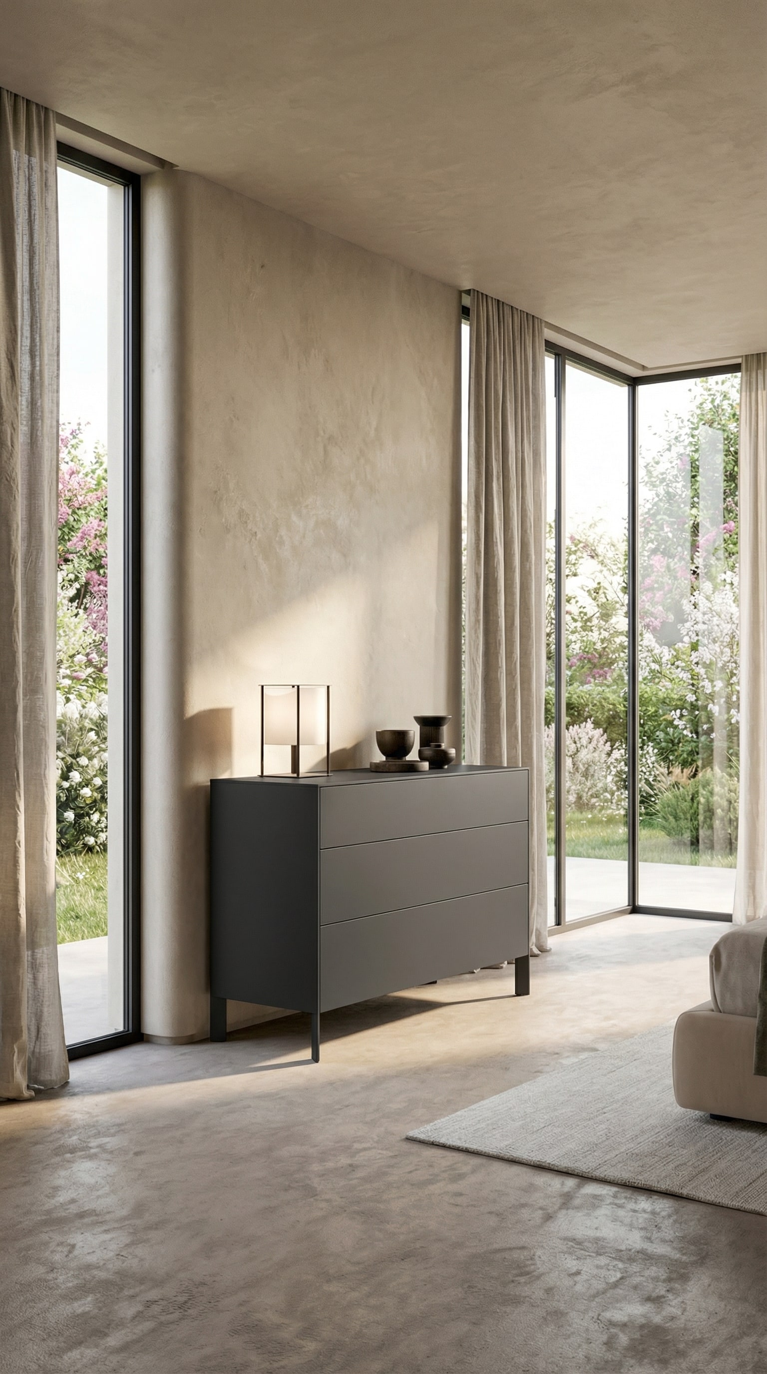Com&ograve; minimalista grigio scuro davanti a una parete beige con una luce primaverile delicata
