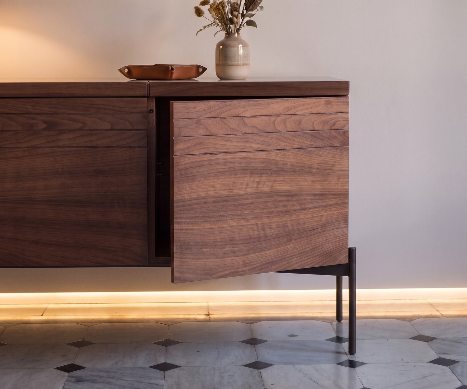 Madia di design al2 o-rizon 003 in noce Madia di design al2 o-rizon 003 in legno di noce con anta push-pull socchiusa in un soggiorno moderno.