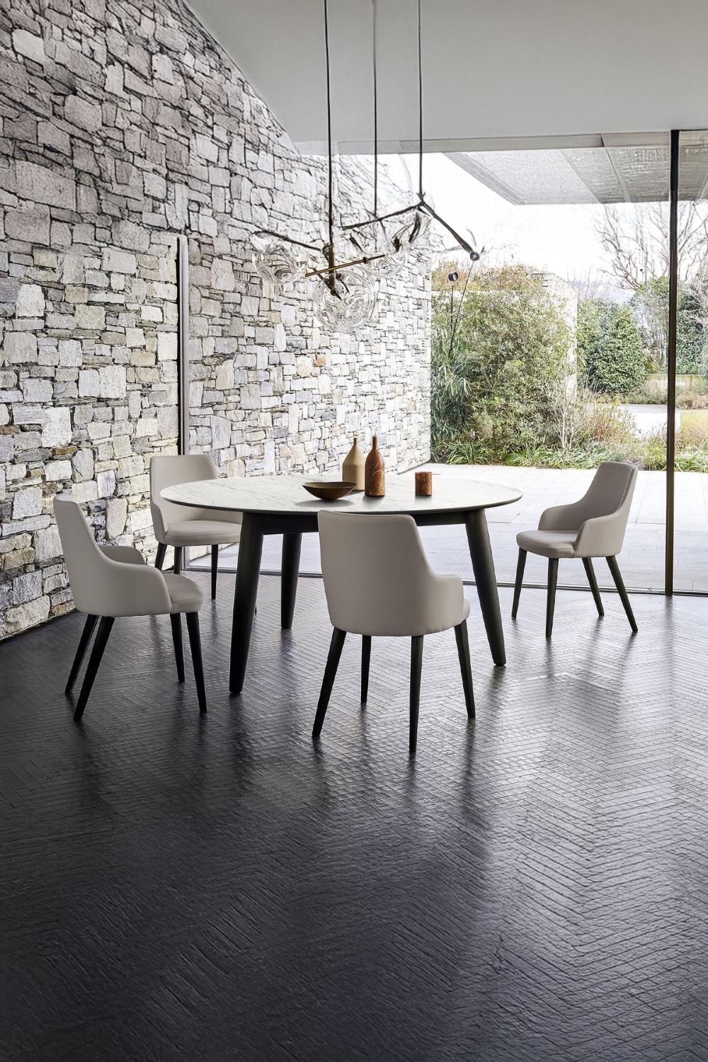 tavolo-da-pranzo-rotondo-e-sedie-curve-in-bianco-e-nero-accanto-a-una-parete-effetto-pietra