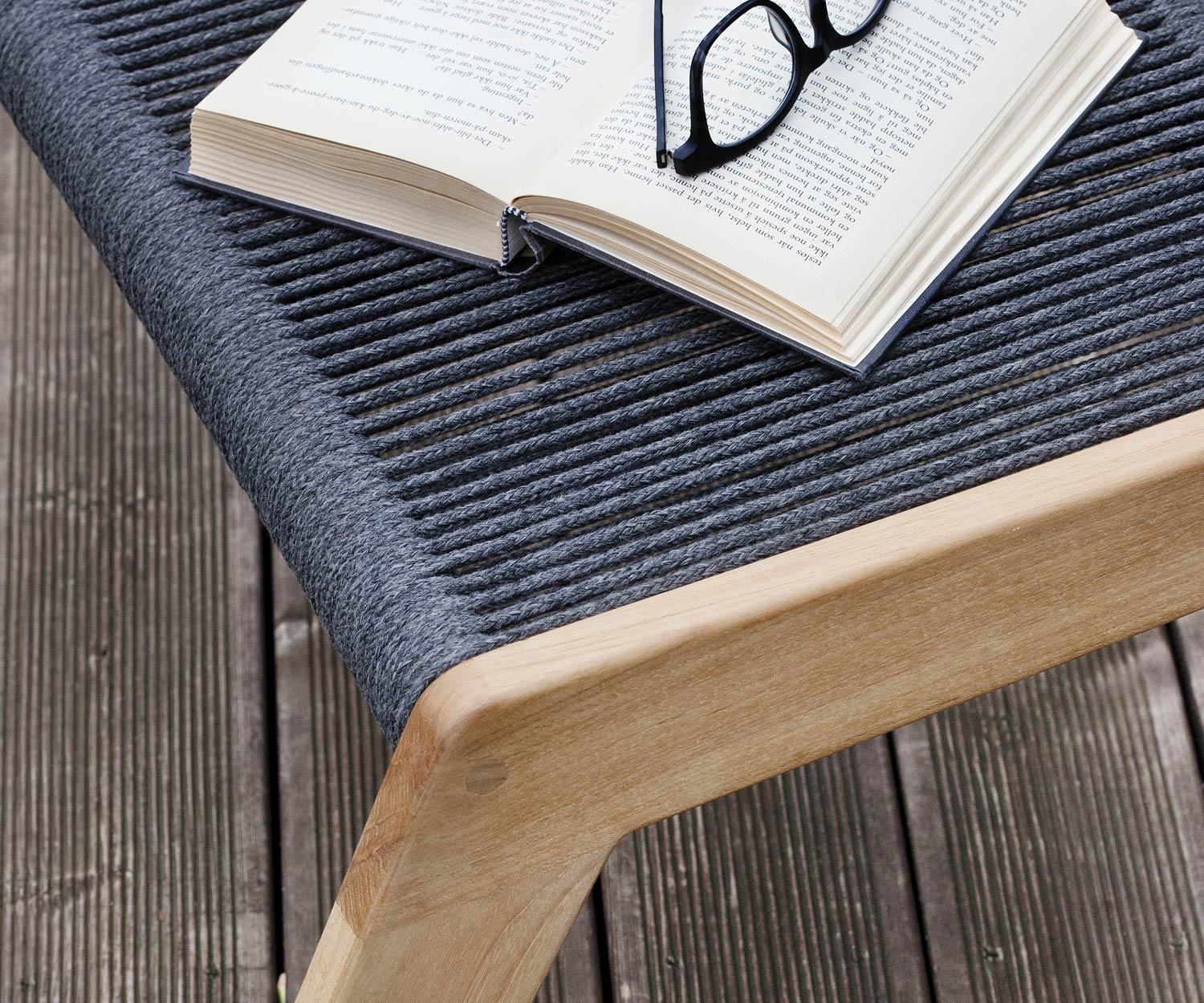 Oasiq Sgabello di design Skagen con cuscino imbottito in grigio scuro davanti alla sedia a sdraio