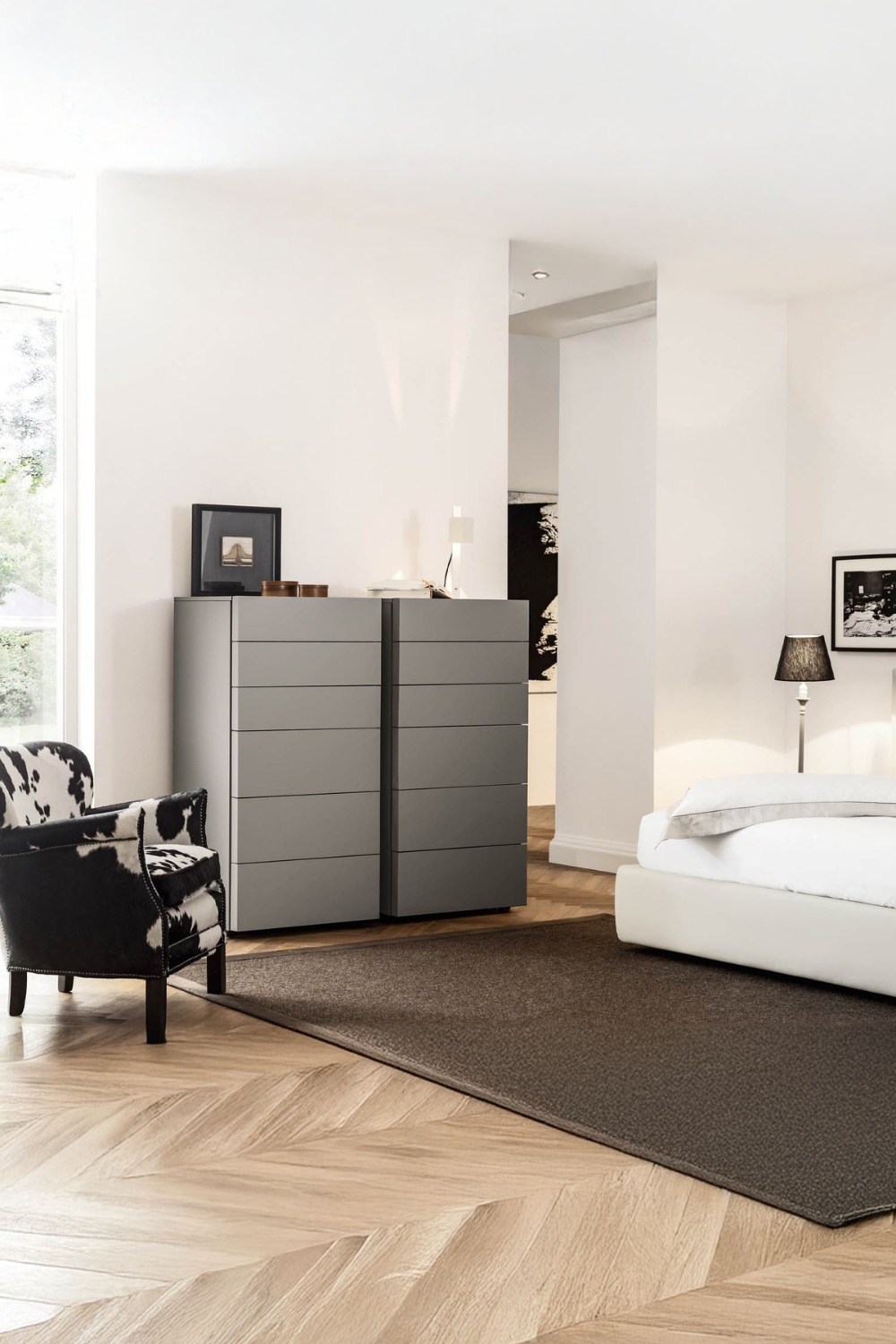 moderna-cassettiera-con-frontali-senza-maniglie-tra-un-elegante-letto-e-una-poltrona-stravagante