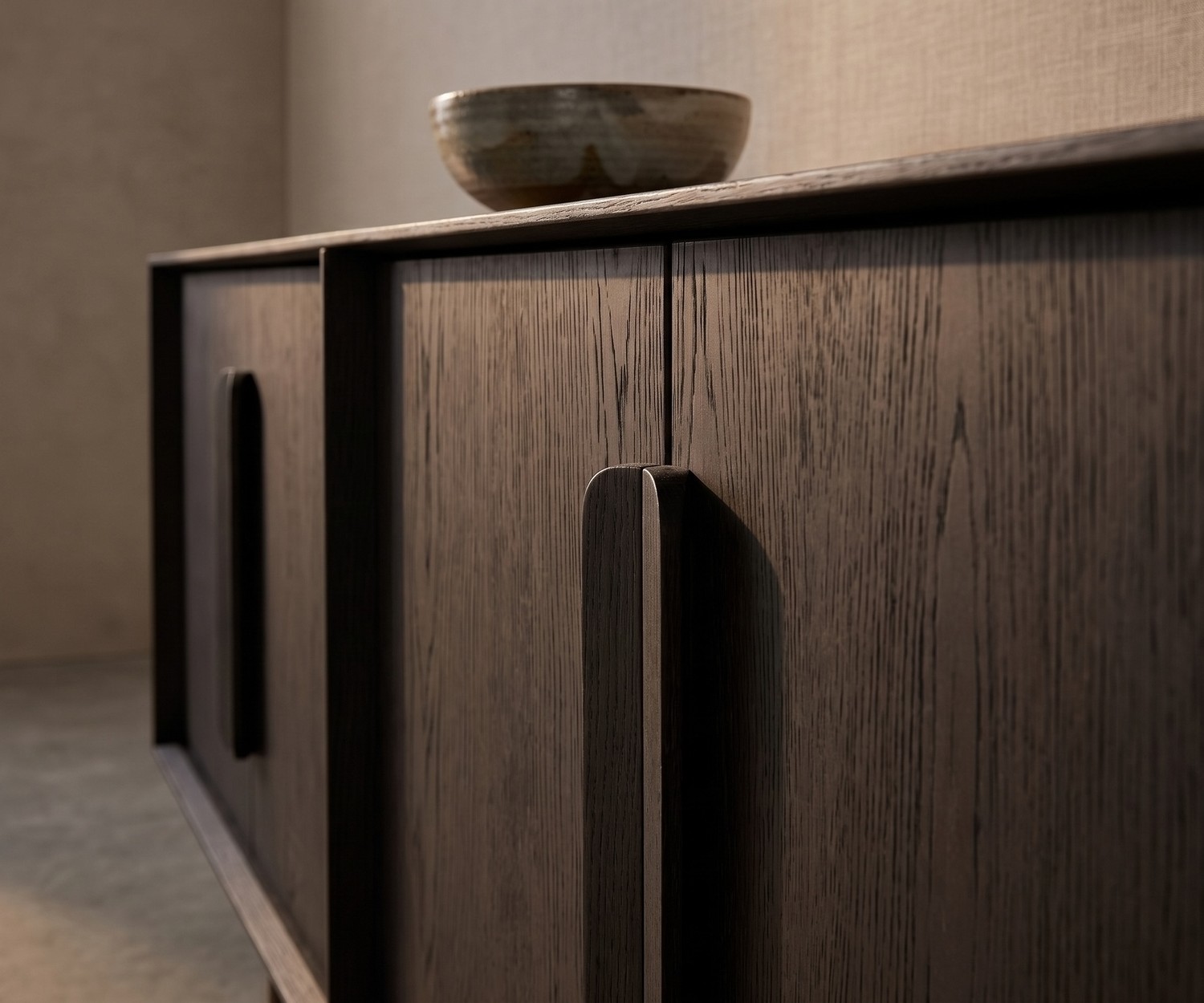Madia al2 Mobius 003 in rovere scuro carbone per il soggiorno, con eleganti maniglie in legno e ciotola decorativa.