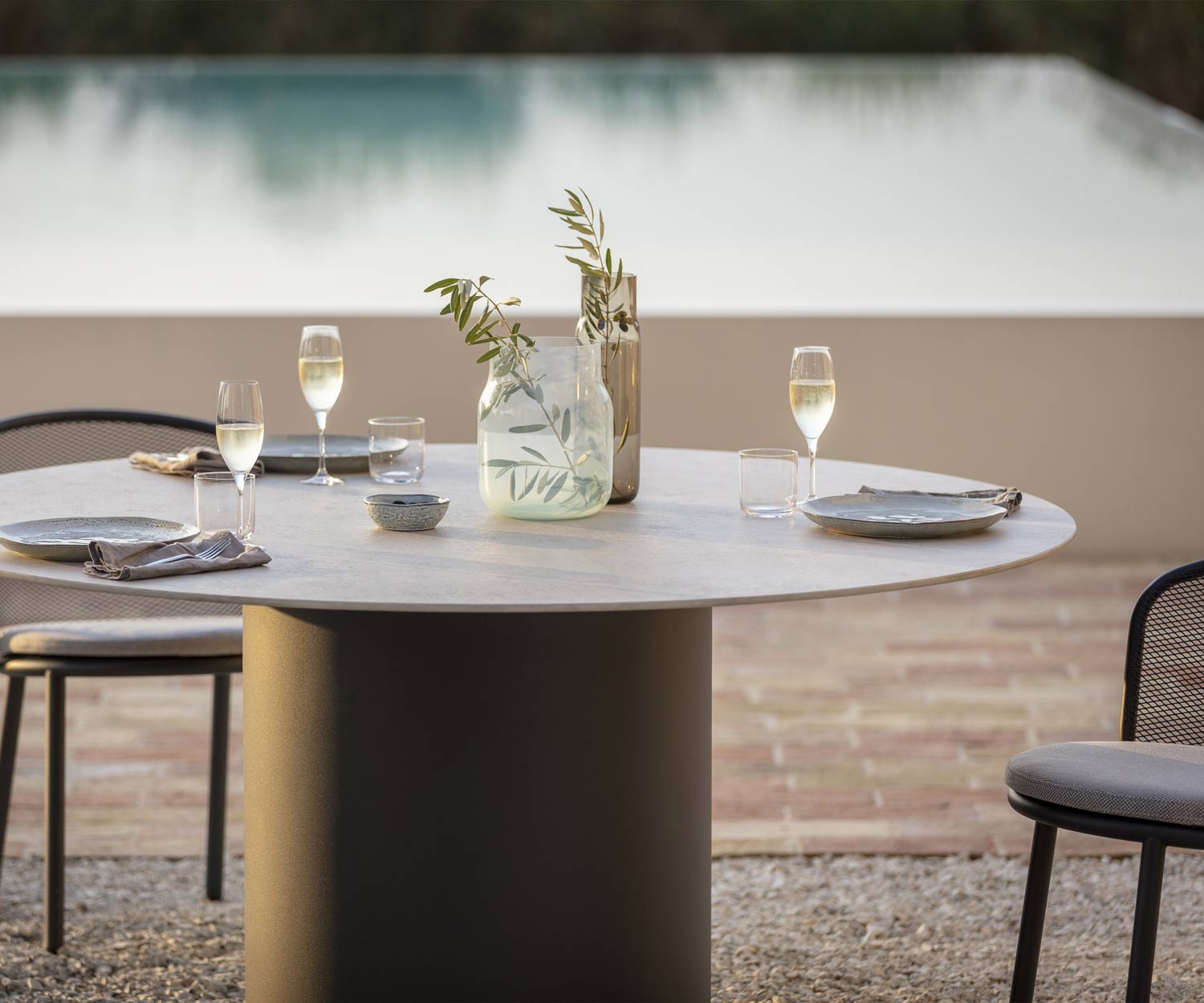 Tavolo da pranzo di Todus con piano in ceramica grigia a bordo piscina su una terrazza in ghiaia