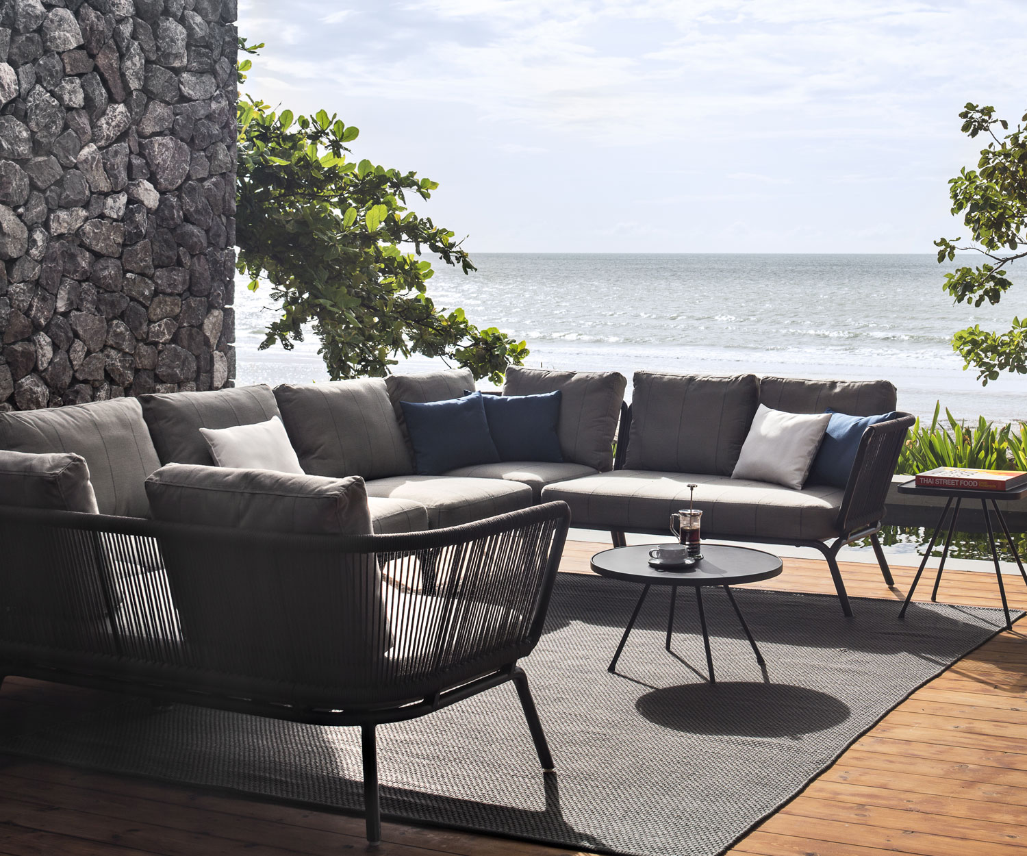 Oasiq Divano design con panca angolare Yland e cuscino imbottito in grigio su una terrazza Oasiq Divano design con panca angolare Yland e cuscino imbottito in grigio su una terrazza
