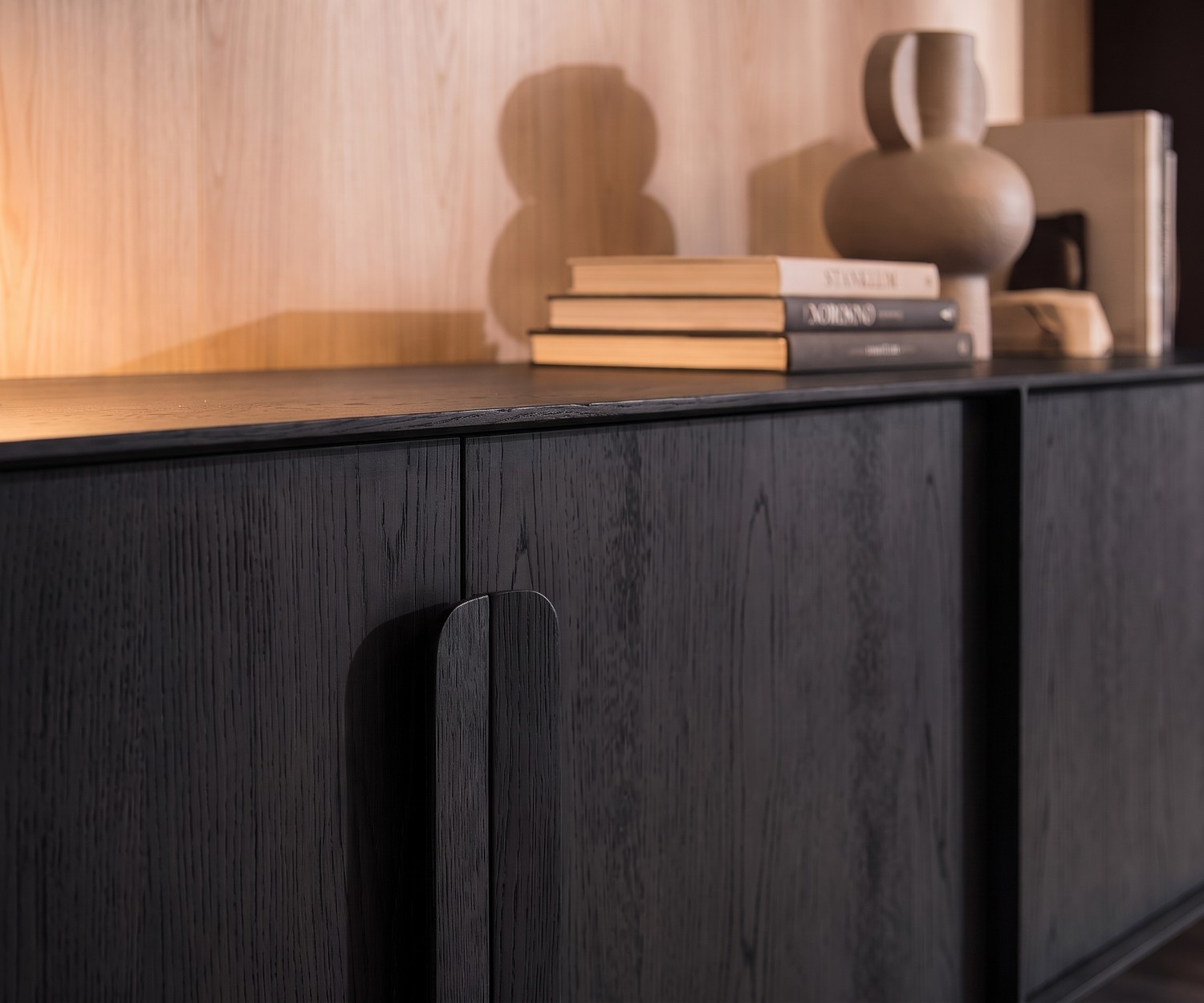 Credenza Mobius 003 di al2 in impiallacciato di rovere nero con maniglie in legno in un soggiorno moderno.