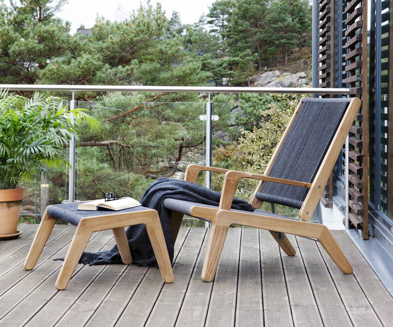 Oasiq Sgabello di design Skagen con cuscino imbottito in grigio scuro davanti alla sedia a sdraio