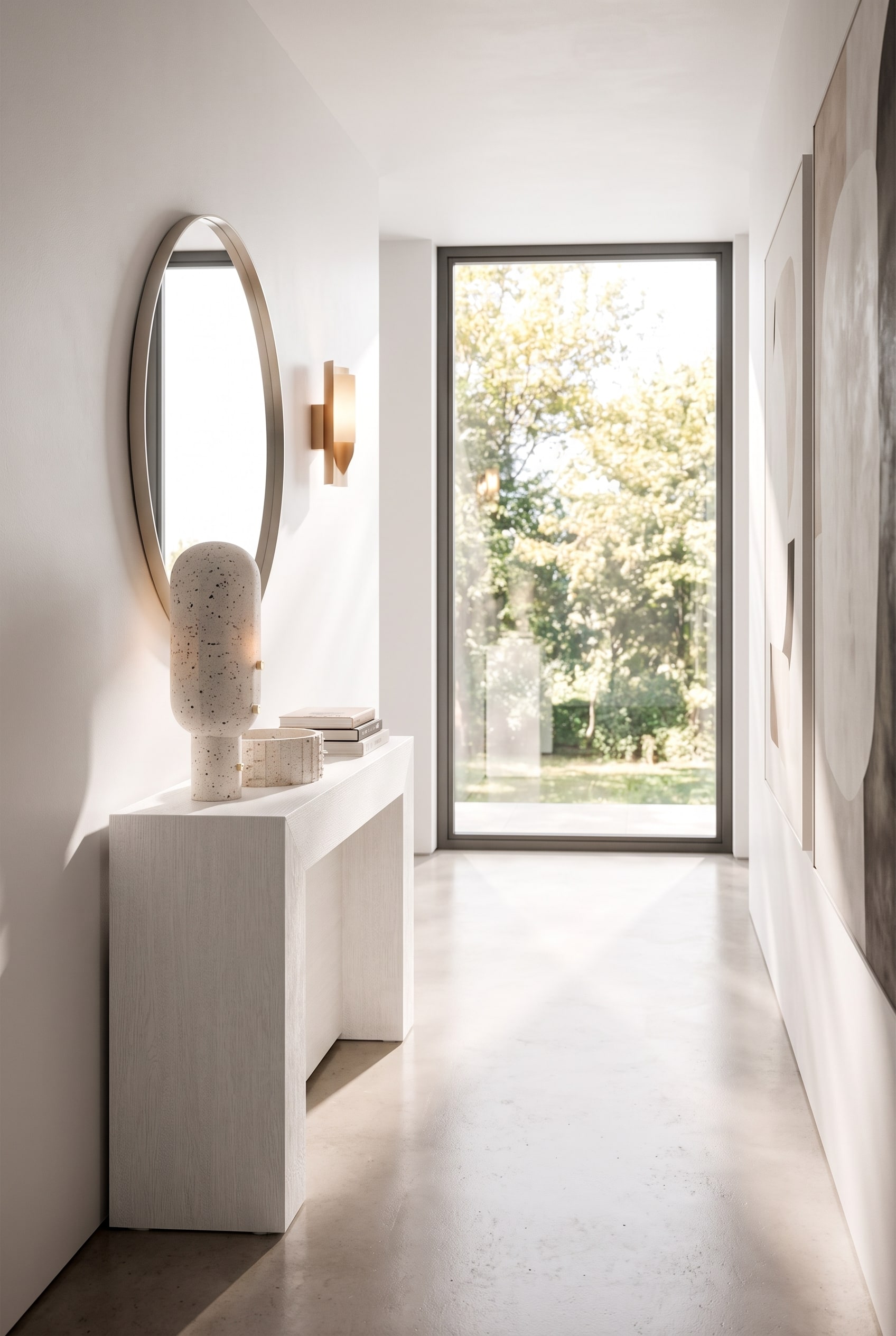 Schmaler Flur mit einer extrem flachen weißen Konsole, darüber ein runder Wandspiegel und eine minimalistische Wandleuchte