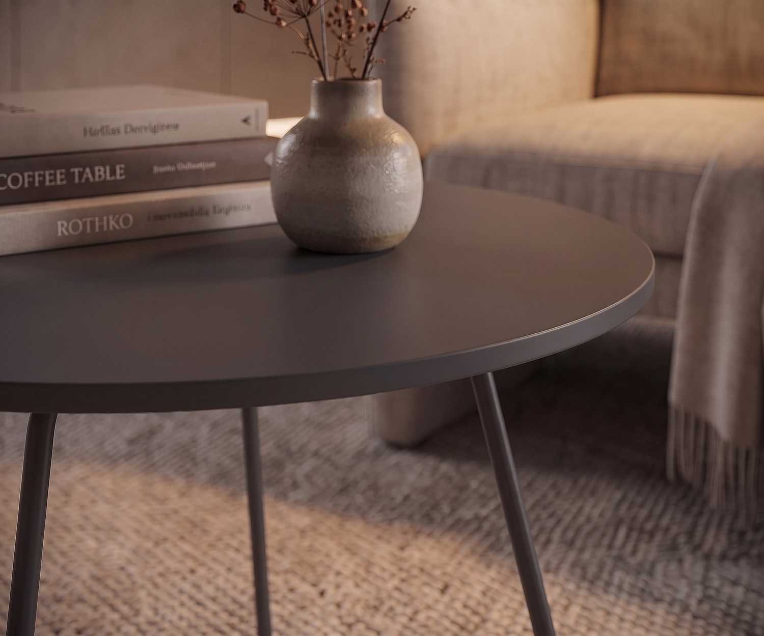 Tavolino da salotto Orbis di Novamobili. Tavolino rotondo grigio accanto alla poltrona con libri e vaso.